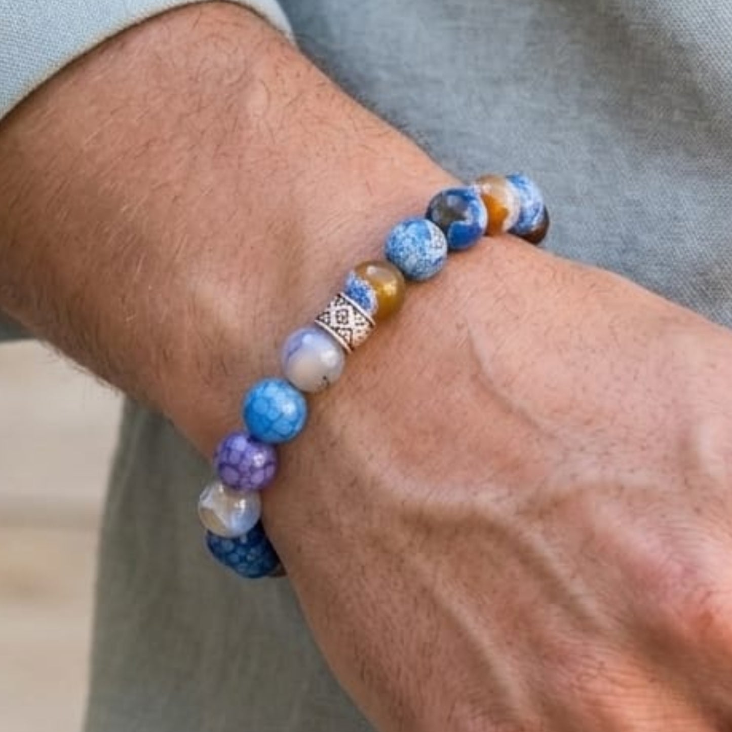 Men's blue agate beaded bracelet with silver-toned geometric charm on wrist