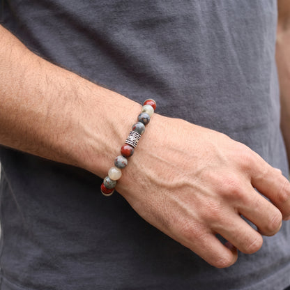 Men's beaded bracelet on wrist: red, cream, and gray natural stone beads with ornate metal clasp