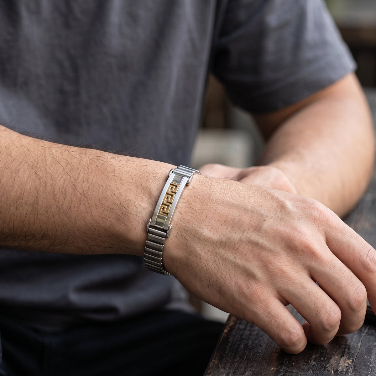 Greek key stainless bracelet with gold inlay and watch clasp on forearm, silver tone