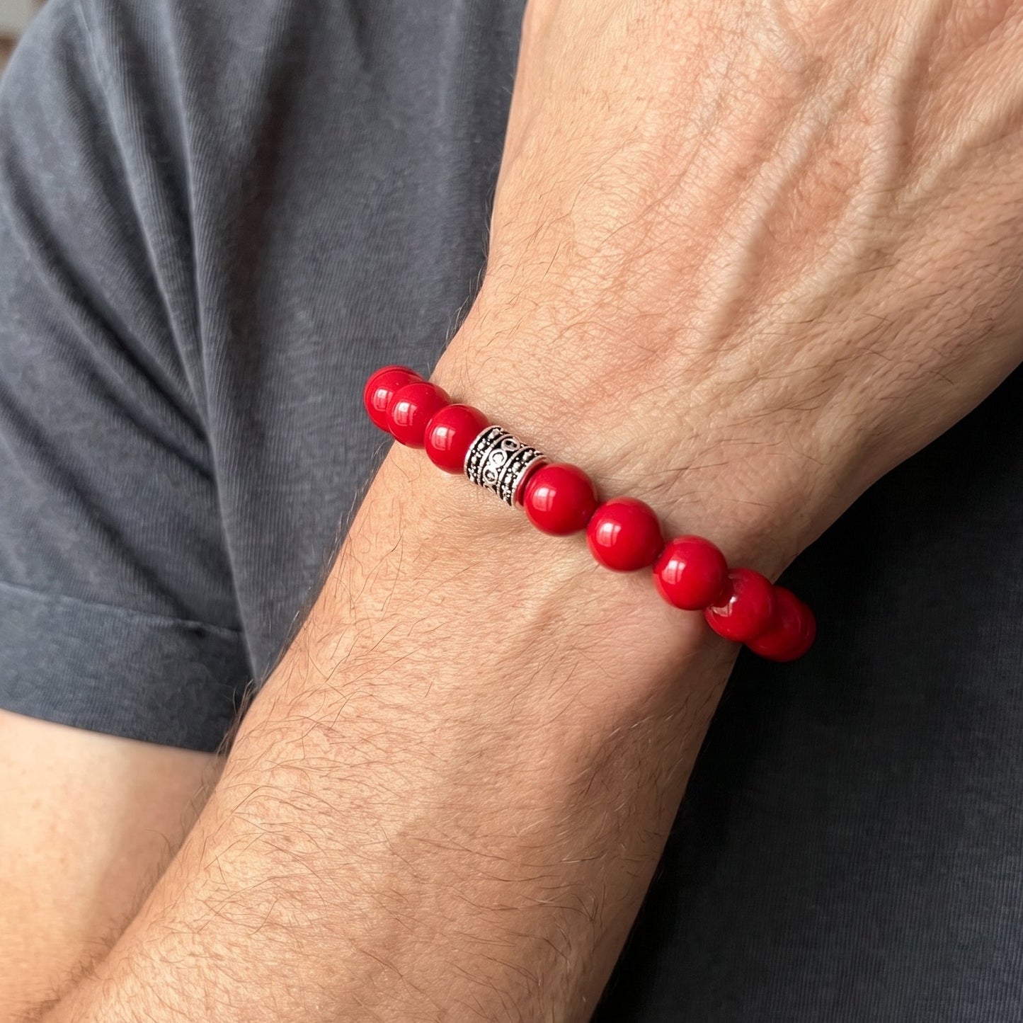 Men's red agate bead bracelet on wrist with silver-tone patterned centerpiece