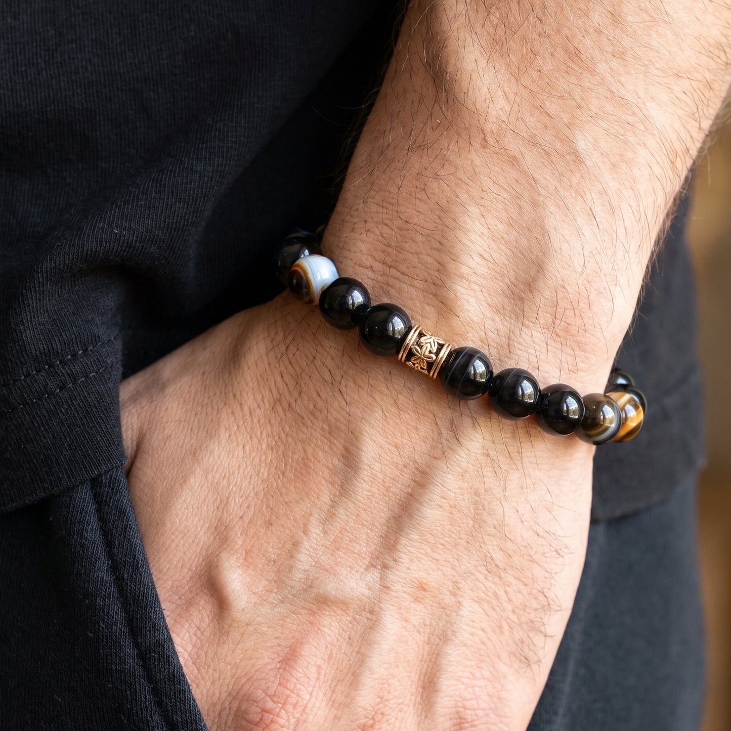 Men's agate bracelet on wrist, dark blue beads with gold-tone center charm