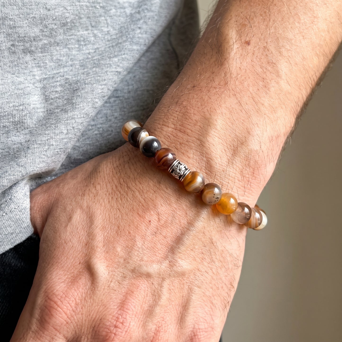 Beaded agate bracelet on wrist with brown, amber, black, and white round beads