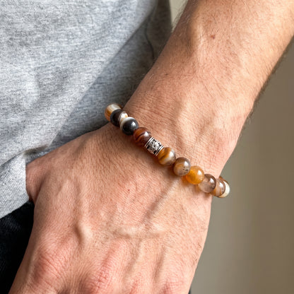 Beaded agate bracelet on wrist with brown, amber, black, and white round beads