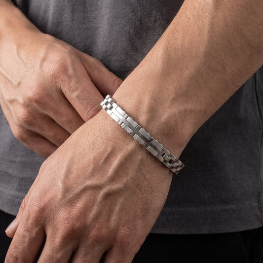 Silver stainless steel link bracelet with geometric cross pattern, close-up on wrist