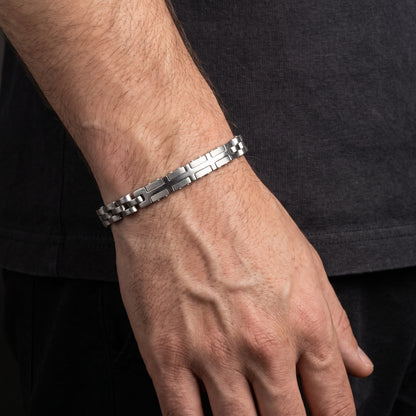 Silver stainless steel link bracelet with checker and cross pattern, worn on wrist
