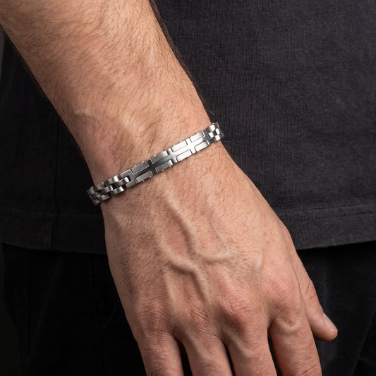 Silver stainless steel link bracelet with checker and cross pattern, worn on wrist