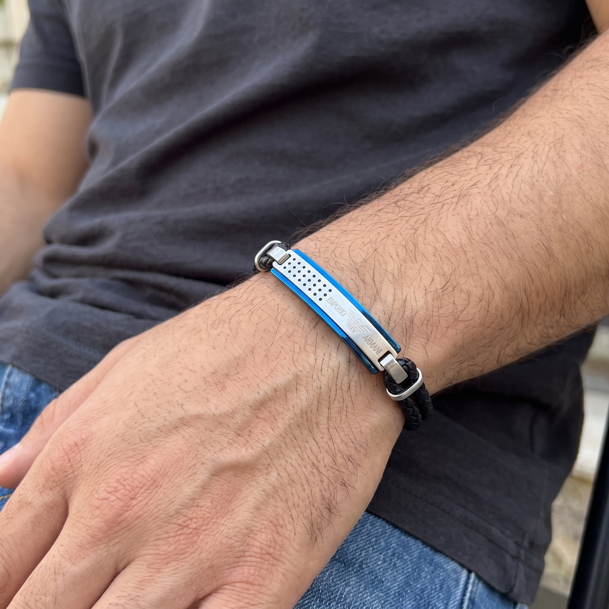 Blue and silver bar bracelet with black braided leather straps on forearm