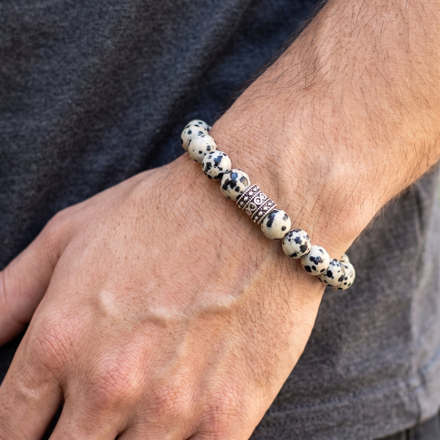 Dalmatian jasper bead bracelet on wrist, black-and-white beads with ornate silver-tone spacer