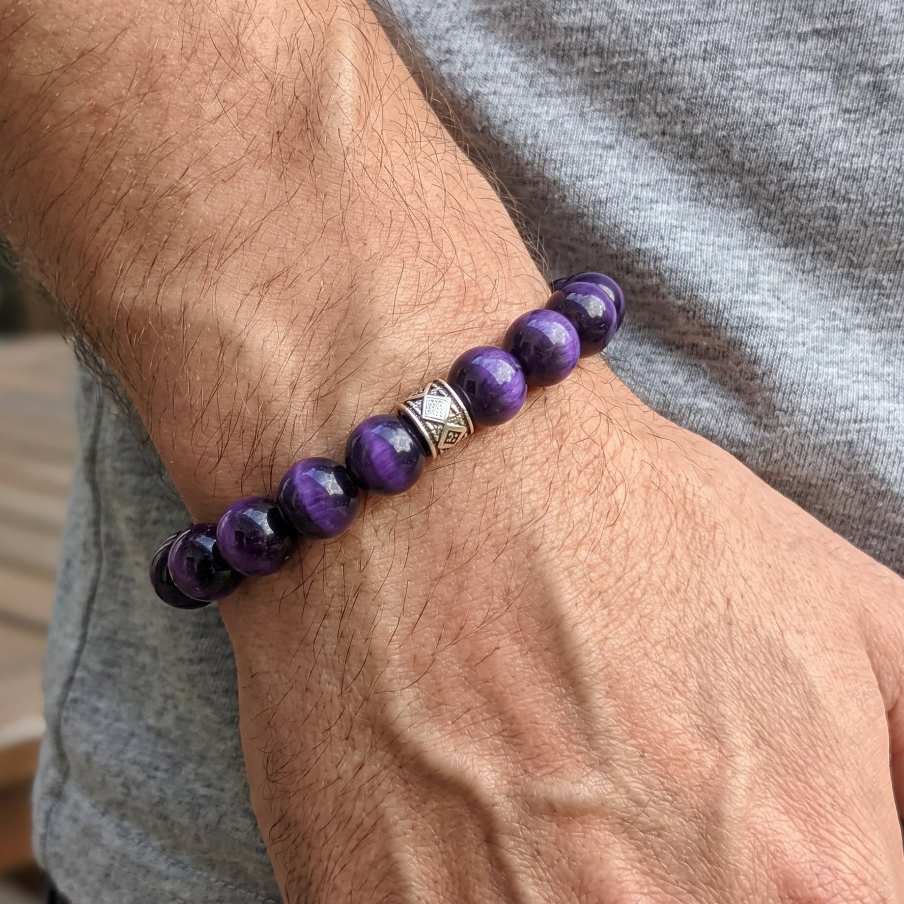 Men's purple tiger's eye bead bracelet on wrist with silver-tone square accent