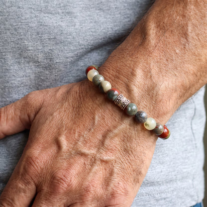 Men's beaded natural stone bracelet on wrist with red and cream beads and gray stone accents