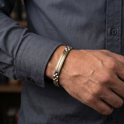Bracelet on man's wrist: silver curb links with gold bars and amber center stripe
