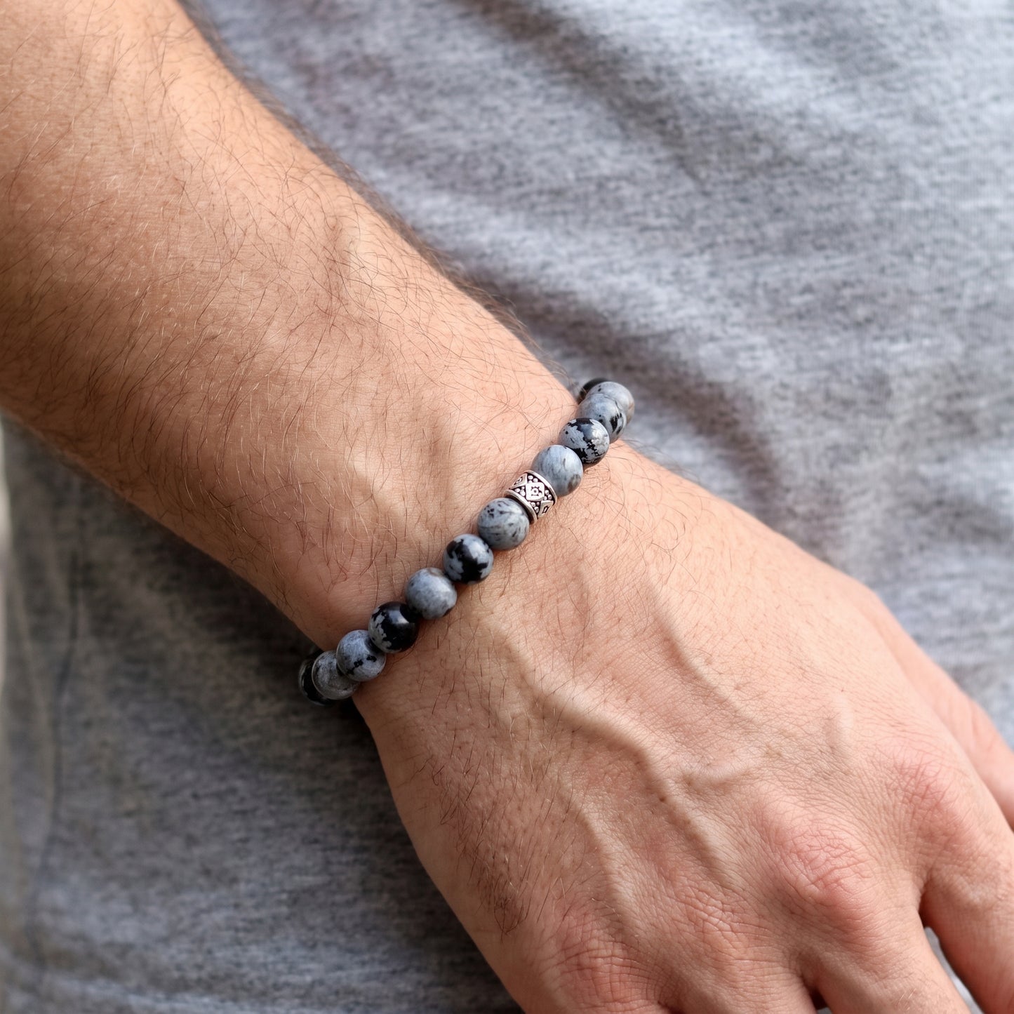 Obsidian bead bracelet worn on wrist; speckled gray stones with black accent beads