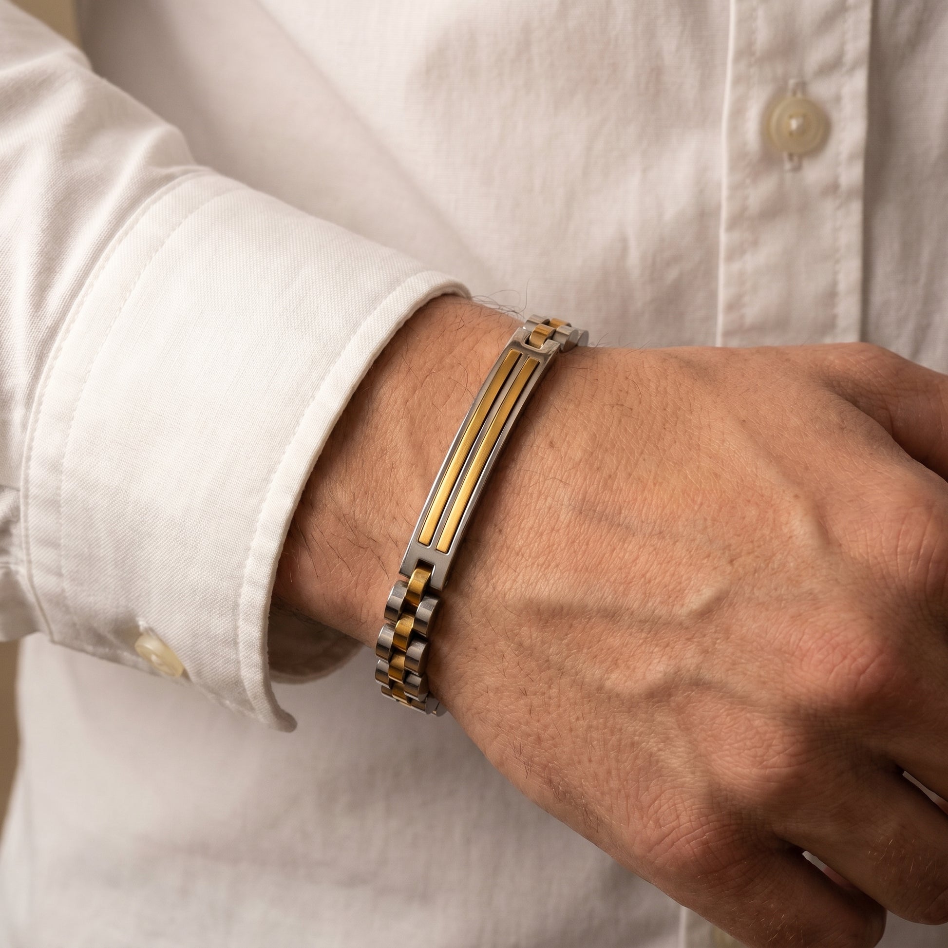 Bracelet on man's wrist: silver and gold stainless steel links with amber stripe