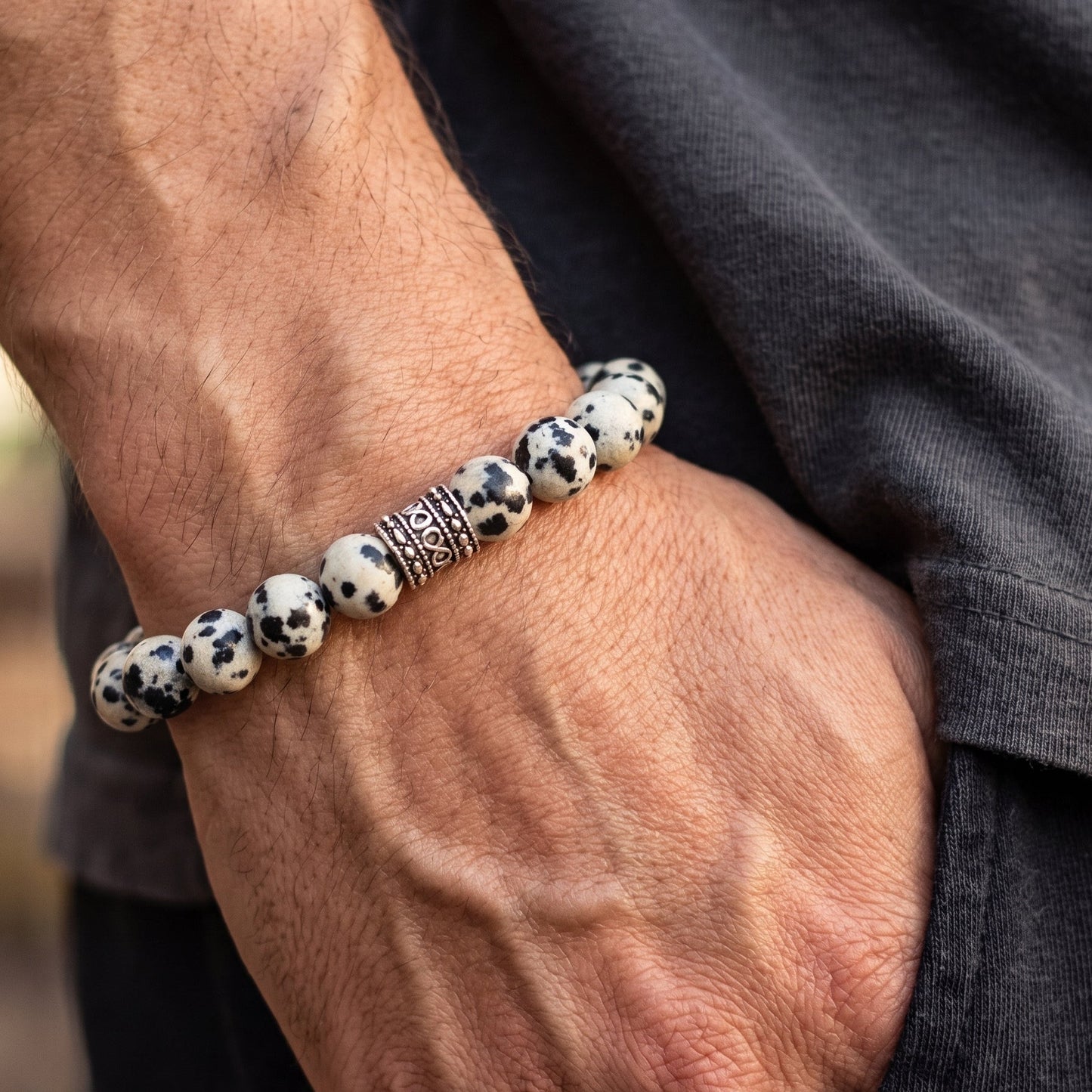 Men's Dalmatian jasper bead bracelet on wrist, speckled beads with silver-tone clasp