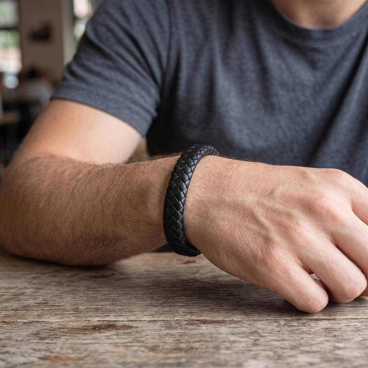 Men’s black braided leather bracelet on wrist with dark woven cuff