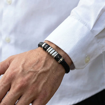 Men's Cobalt Nexus Bundle B-124 B-87 bracelets featuring a black braided band and metallic accents, worn on a wrist.