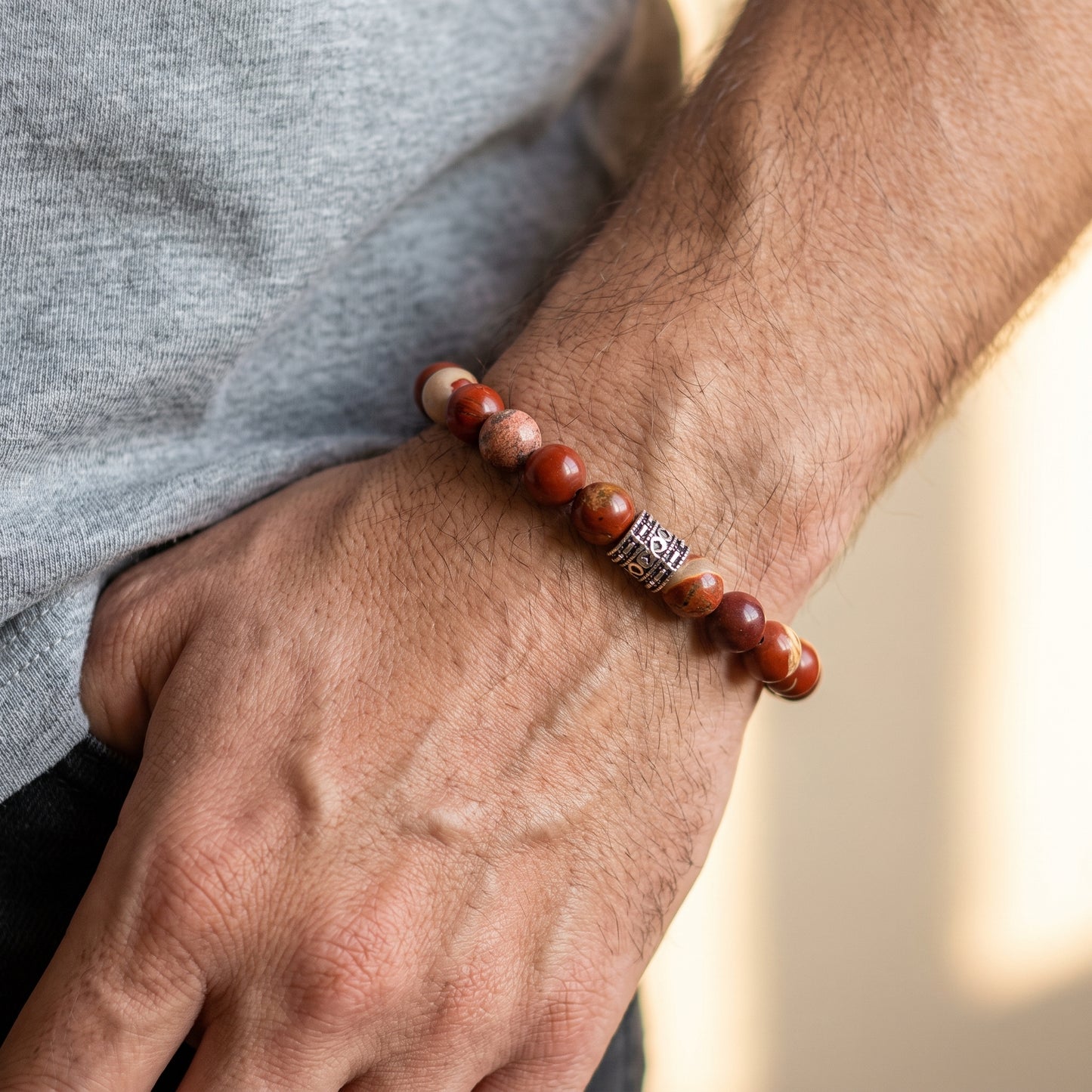 Red jasper stone bracelet on forearm with mixed red beads and silver-tone clasp detail