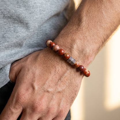 Red jasper stone bracelet on forearm with mixed red beads and silver-tone clasp detail