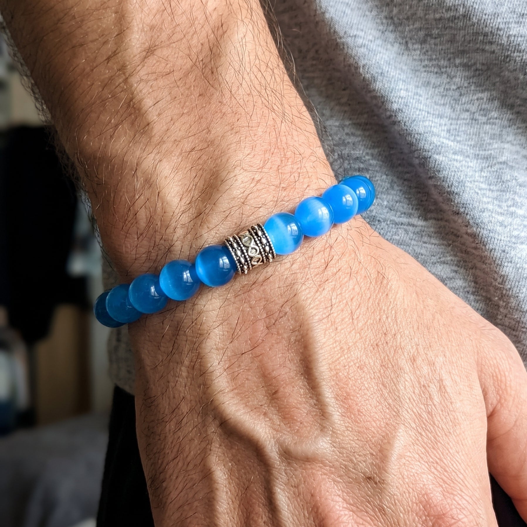 Men's blue agate bead bracelet on wrist with dark metal accent spacer.