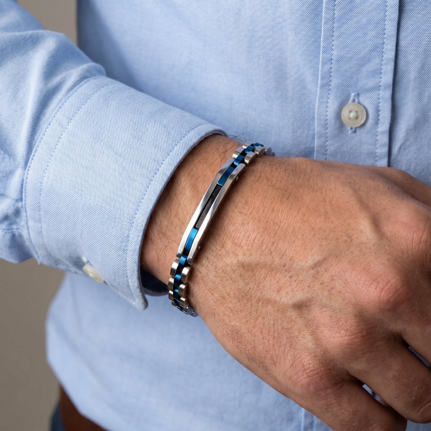 Blue-accent stainless steel bracelet on wrist with light blue shirt cuff