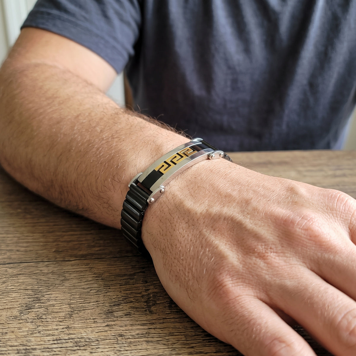Men's Greek key bracelet with black steel links and gold accents, silver clasp details