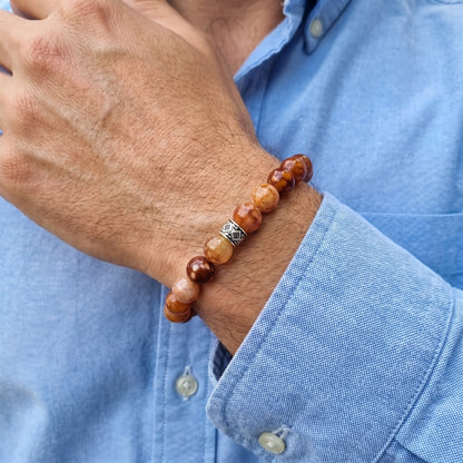 Men's brown stone bead bracelet worn on wrist with silver patterned spacer detail