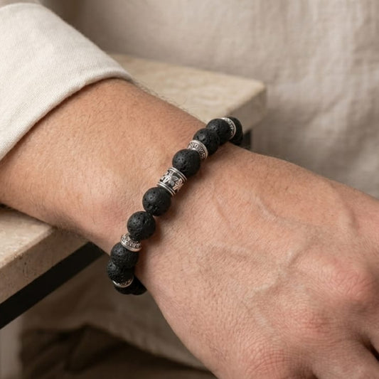Men's lava stone bead bracelet on wrist with silver-tone barrel and bead separators