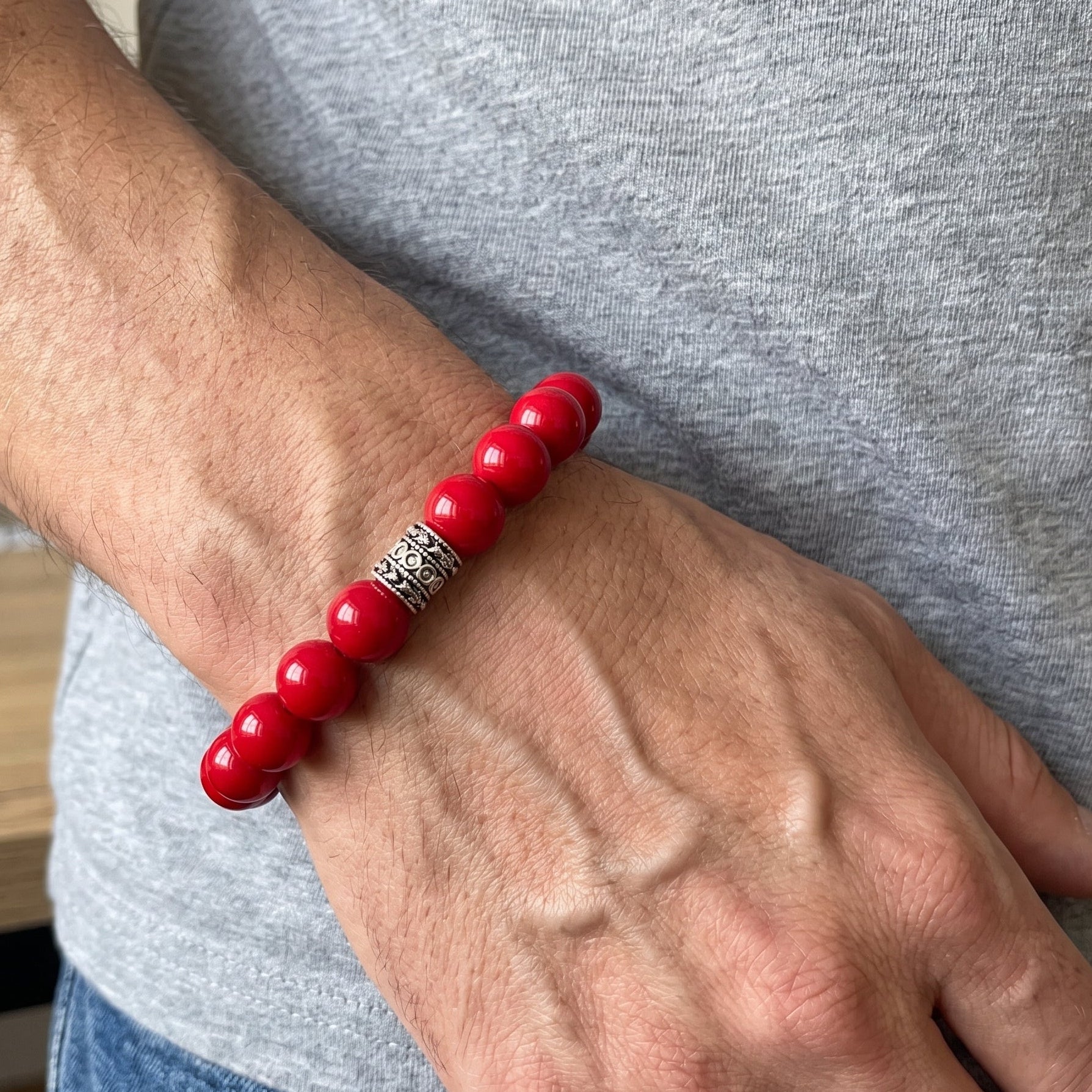 Red beaded agate bracelet on wrist with silver-tone patterned center