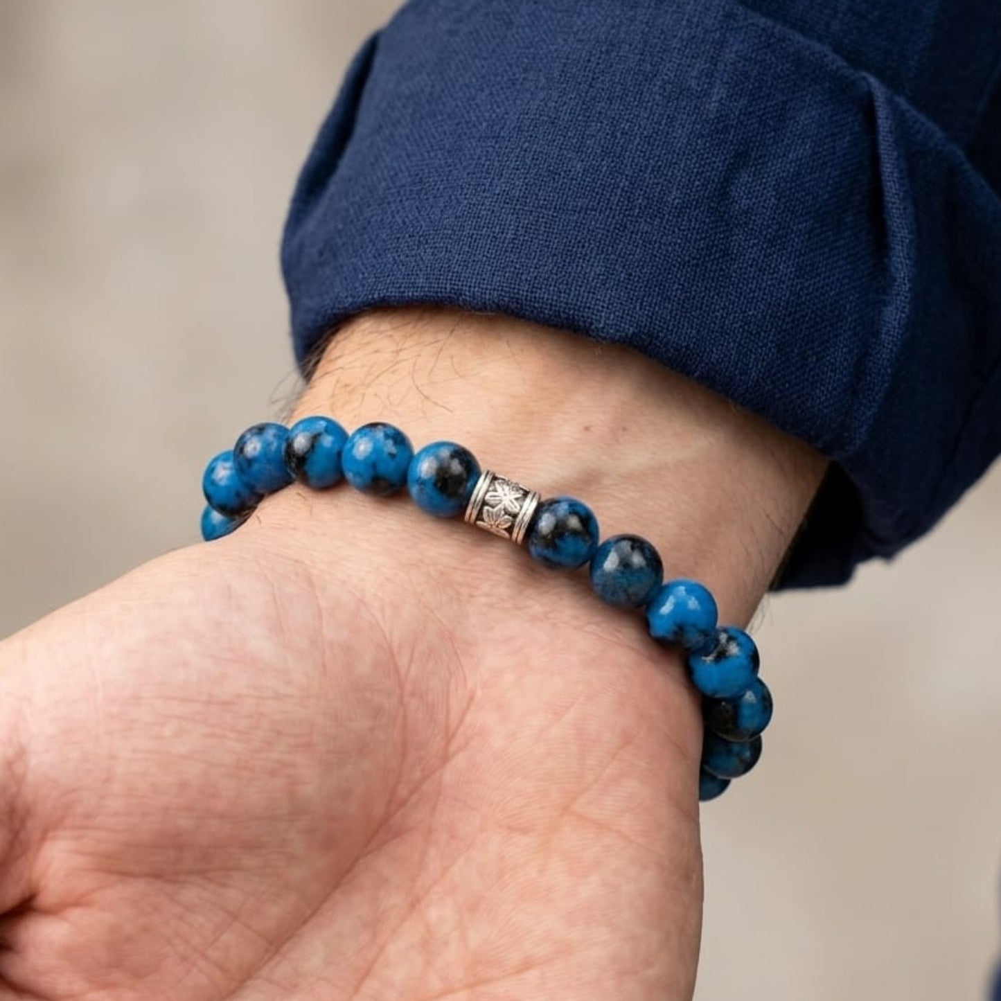 Men's stone bead bracelet worn on wrist with dark blue shirt sleeve
