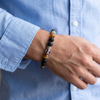 Stone bracelet worn on wrist with black lava and orange beads and silver-tone center spacer