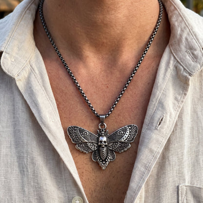 Silver-tone butterfly skull pendant necklace worn on chest over light shirt