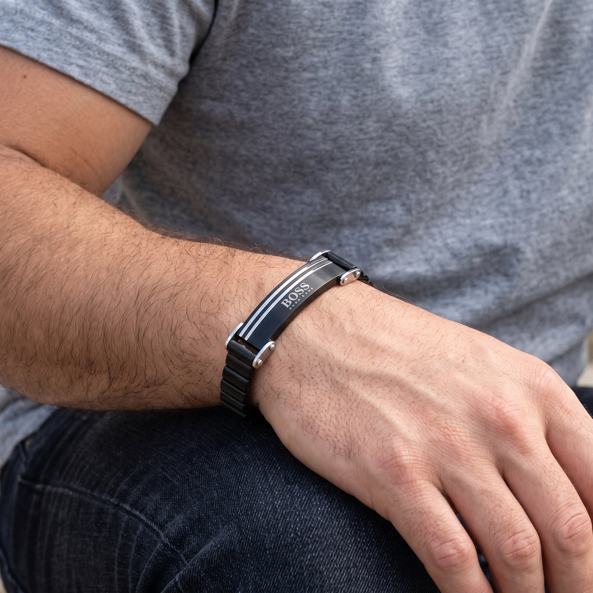 Men's black stainless steel ID bracelet with silver lines and clasp on wrist