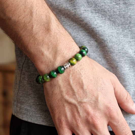 Green tiger's eye stone bead bracelet worn on wrist with silver-toned clasp centerpiece.