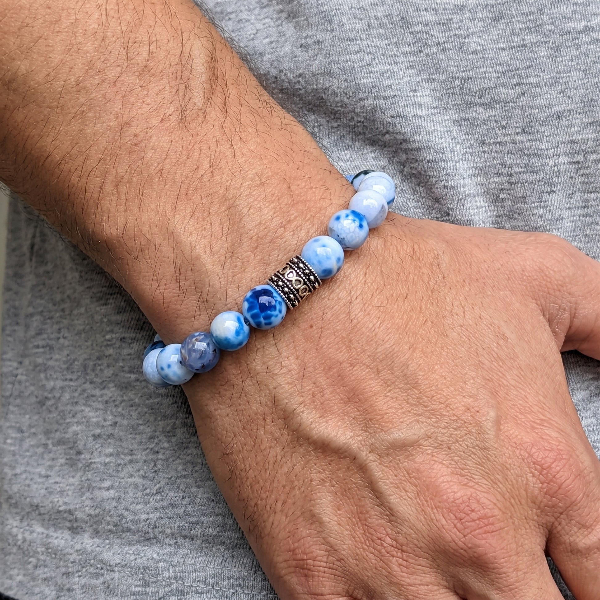 Close-up of blue agate bead bracelet on wrist featuring a black patterned metal spacer.
