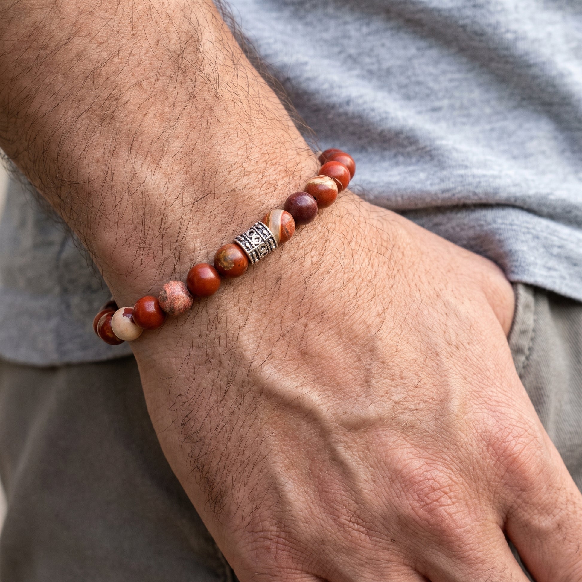 Red jasper beaded bracelet worn on wrist with silver-tone center clasp and round stone beads