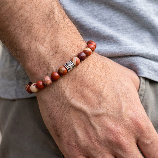 Red jasper beaded bracelet worn on wrist with silver-tone center clasp and round stone beads