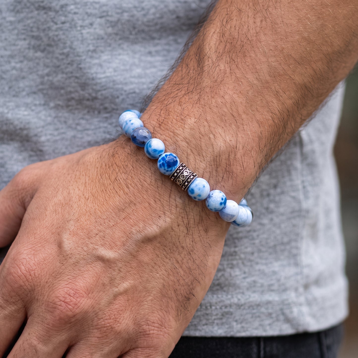 Blue-and-white agate bead bracelet on forearm with black engraved centerpiece spacer.