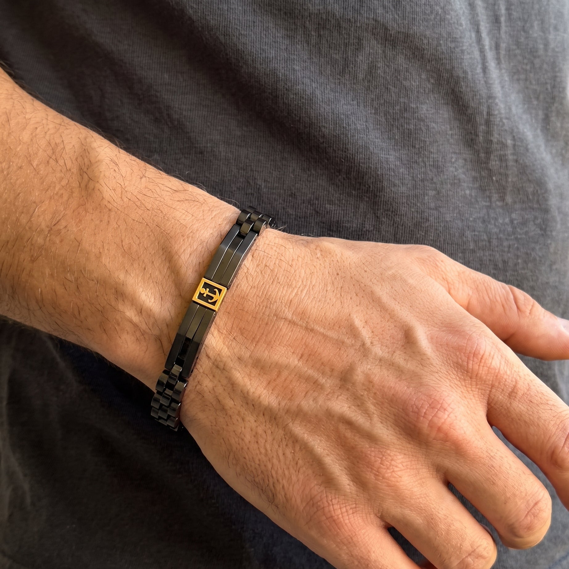 Men's black stainless steel bracelet with gold anchor charm, worn on wrist