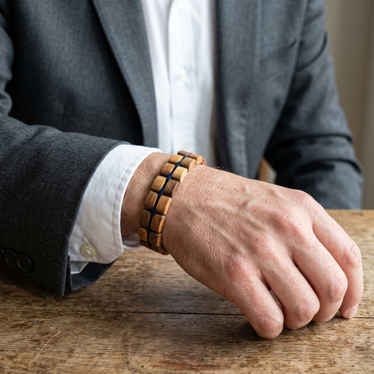Men's walnut wood bracelet with dark bead segments, adjustable wrap on wrist