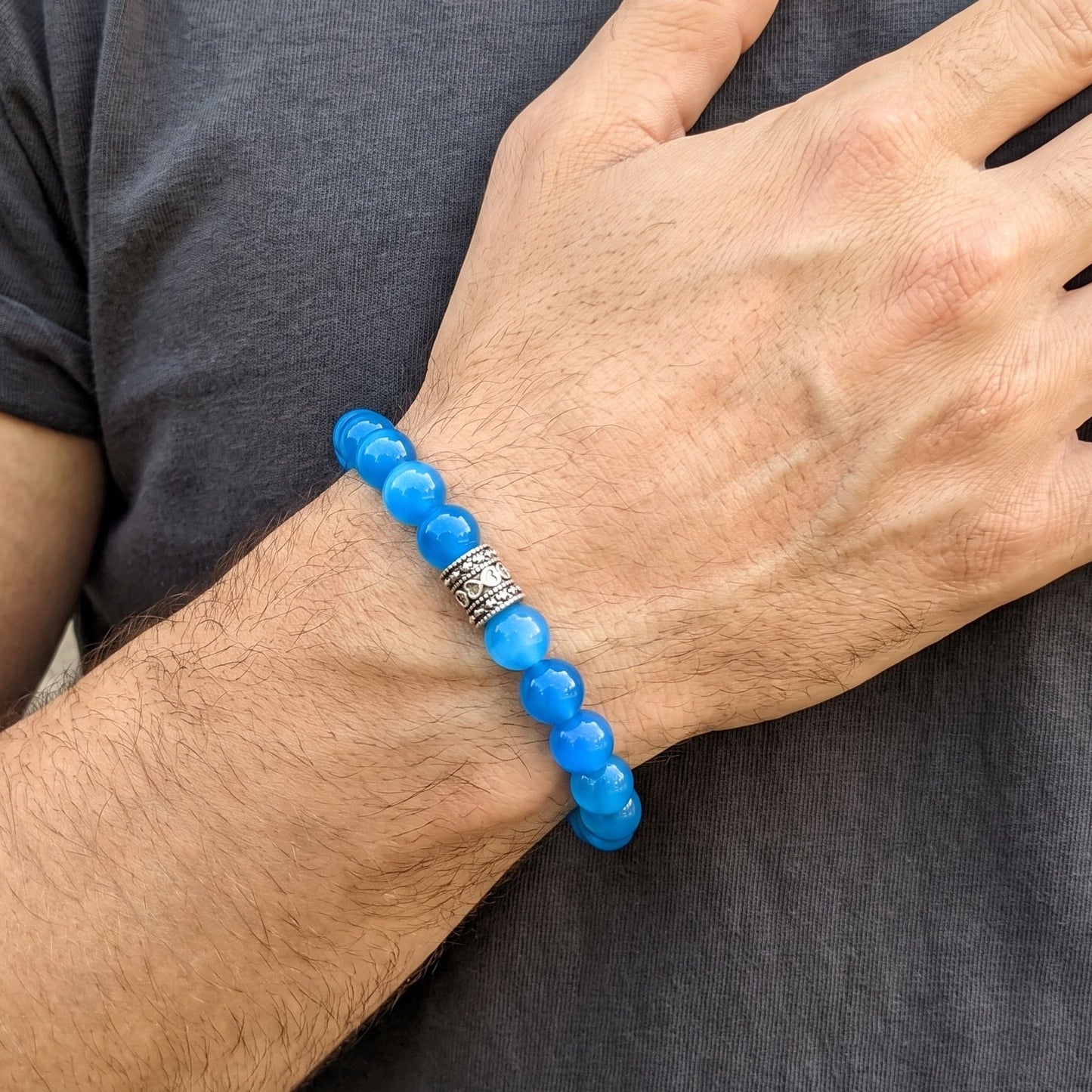 Blue agate bead bracelet worn on both wrists with dark metal centerpiece.