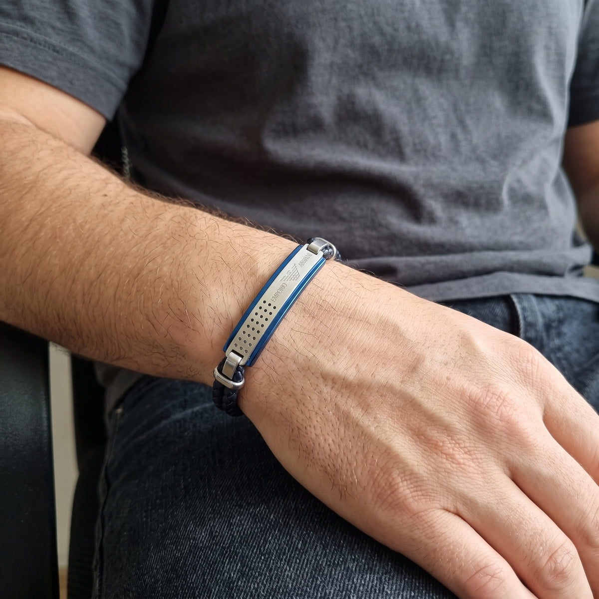 Braided leather bracelet featuring blue strip and silver end pieces on wrist