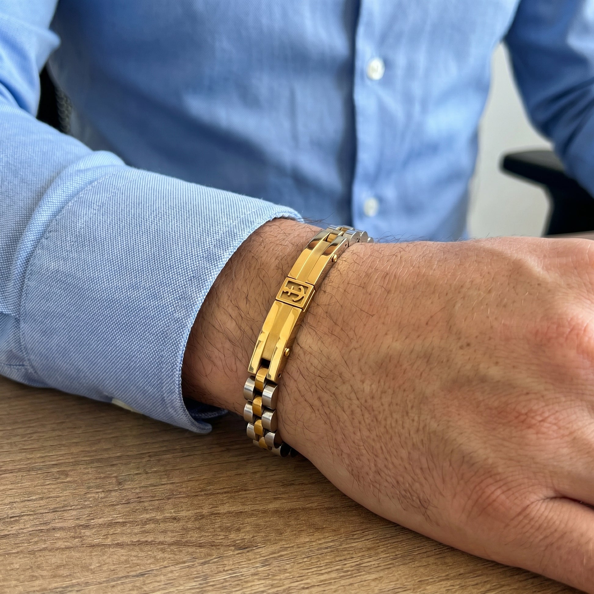 Anchor bracelet on forearm in two-tone gold and silver with gold center bar and silver links