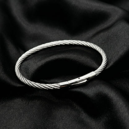 Silver stainless steel bracelet with a magnetic clasp, featuring a twisted wire design, set against a black fabric background