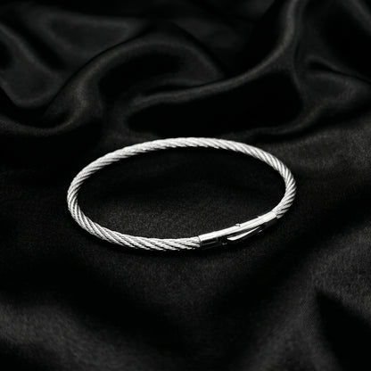 Silver stainless steel bracelet with a magnetic clasp, featuring a twisted cable design, displayed on a black satin backgroun